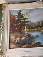 Close-up of upper-left and bottom-left corner of painting and frame showing autumn trees and river scene