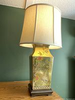 Front and side views of Asian inspired tri-light lamp with antiqued gold finish featuring bird and floral designs on rectangular body.