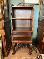 Front view of walnut curio/bookstand showing shelves, drawers, legs