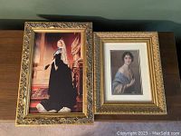 Two framed portraits side by side on a wooden surface; left is Queen Victoria, right is Duchess of York Elizabeth.