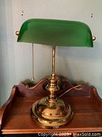Front view of the vintage bankers lamp showing the green glass shade and brass base with pull chain.