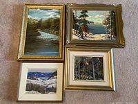 Group shot of four framed landscape paintings on carpet