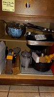 Various baking pans, cookie racks, graters, measuring cup and other kitchen utensils on a wooden shelf