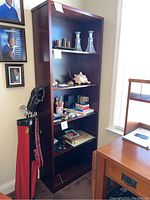 Full view of the tall wooden bookshelf loaded with various items to show size and shelving arrangement.