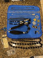 Entire lot of costume jewelry displayed on blue towel including necklaces, pins and earrings organized by type.