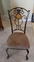 Full view of a dining chair showing stained brown upholstered seat, metal frame, and decorative back with wooden accent.