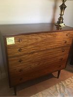 Front view of the four-drawer wooden dresser showing wood grain and diamond-shaped drawer knobs