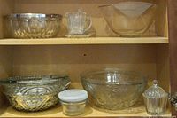 Glass bowls and serving items displayed on wooden shelf showing variety and detail
