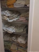 Closet shelves filled with folded towels, sheets, and blankets in multiple colors and types