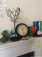 Wide view of mantel showing metal tree sculpture, blown glass fish, clock, and decorative Christmas boxes and tins