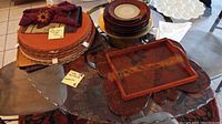 Overview of placemats, plates, napkins, napkin rings, and wooden tray on glass table