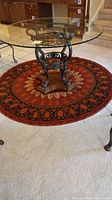 Full view of the round rug under a glass-top table, showing pattern and size relative to furniture.