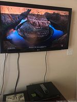 Front view of LG 42-inch TV mounted on wall showing a nature scene with rocky river and water.