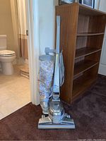 Full view of upright vacuum showing base, handle, cloth bag and cord