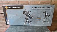 Front of sealed retail box showing Celestron branding, AstroMaster 114AZ name, and key features