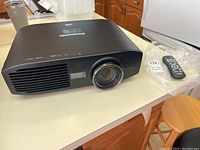 Front and top view of projector alongside remote on white countertop