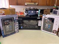 Overview showing two La Crosse Technology forecast station boxes, boxed Grundig G2 Reporter and Grundig S450DLX field radio unit