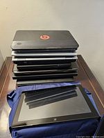 Stack of seven laptops topped by a black HP Pavilion DM4-3099SE BeatsAudio laptop, Samsung 700T tablet placed in front