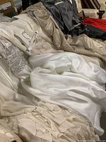 Multiple evening dresses in various colors and fabrics laid out, showing different styles and textures.