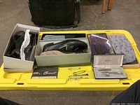 Lot contents on yellow surface showing shoes in boxes, sashes, kerchiefs, and kilt pins.