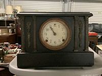 Front view of the vintage wooden mantle clock showing rectangular case with gold decorative accents and columns, black finish.