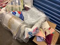 Full view of assorted table linens including rolled and folded tablecloths and napkins on a chair.