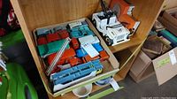 Box of assorted toy vehicles including trucks and construction vehicles, some with ladders and equipment, assorted colors.