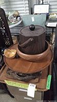 Large wood trays, faux wood ice bucket with tongs, wood Lazy Susan, and wood bowls grouped on shelves and chair