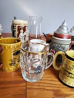 Photo showing front view of the seven beer glasses and steins on a light background.