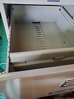 Open drawer showing metal rails for hanging file folders in a metal filing cabinet.