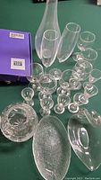 Overview of glassware lot showing variety including tall canister, champagne flutes, smaller glasses, and serving dishes