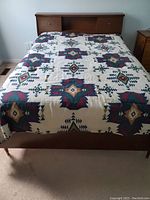 Full view of assembled double bedframe with patterned bedding on top, showing headboard with built-in shelves and footboard with tapered legs.