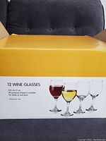 Closed cardboard box showing 12 wine glasses label with image of different filled wine glasses and product description.