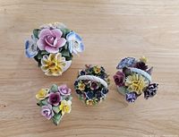 Top down view of 5 Royal Stratford flower porcelain figurines on wood surface showing varied flower arrangements and bases.