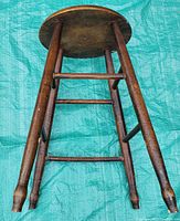 Photo of round wooden mid-century stool showing base and legs with round seat.