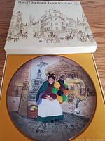 Royal Doulton Character Plate in original box showing the illustrated scene of a balloon seller woman in a street setting.