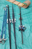 Two sets of black adult cross country skis with white bindings and four blue ski poles with white grips, displayed on a green tarp.
