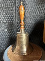 Photo of large brass ship's bell with wooden handle and engraving Titanic 1912 London.