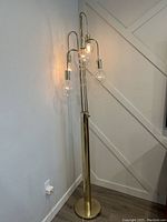 Full view of the polished brass floor lamp showing five curved arms and bulbs