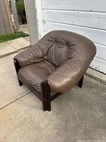 Angled view of brown leather armchair on concrete pad