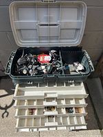 Open Plano tackle box showing multiple vintage fishing reels inside with various fishing tackle in compartment trays below