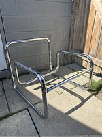 Empty chrome tubular chair frame outdoors against cinder block wall