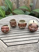Front view of all four items showing the pig, bear, elephant mugs and piggy bank on wooden table outside