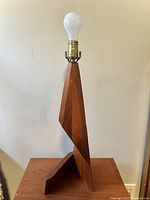 Front view of teak zigzag table lamp showing full height with bulb and brass socket