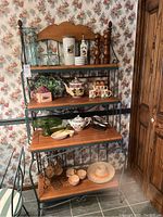 Front view of bakers rack showing all four wooden shelves with items on them not included.