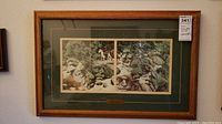 Framed print visible on wall showing two horses with riders in forest setting, wooden frame with green matte.