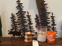 Photo showing metal tree and moose art with wooden candle holder and two decorative candles