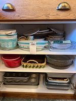Shelved assortment of CorningWare with blue floral pattern, glass dishes, and metal pans