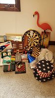 Full lot displayed on carpet with dart board, flamingo, party hats, and assorted games