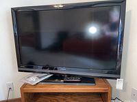 Front view of the Hitachi Ultravision 42-inch LCD TV on its stand, showing the screen and remote placed on front.